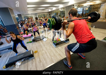 Fitness instructor doing squat exercises during Body Pump fitness class at the gym Stock Photo