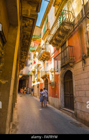 Sicily street, view in summer of a young couple walking in a narrow street in historic Ortigia, Syracuse (SIracusa) Sicily, Stock Photo