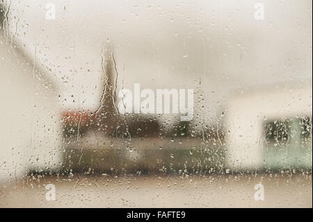 church and spire of church against skyline looking out from very wet rainy window with drops droplets running down glass pane Stock Photo