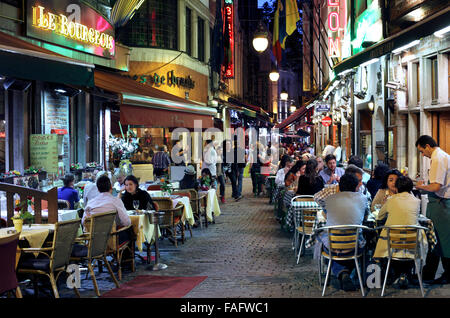 Restaurant tables spill out on to the pavement in Rue des Bouchers, a pedestrian back street in the old centre of Brussels. Stock Photo