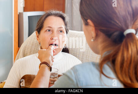 Adult woman giving the cough syrup to elderly mother at home Stock Photo