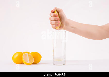 Female hand squeezing piece of orange to get juice. Stock Photo