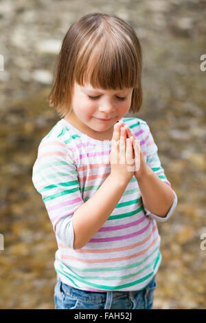 Cute little girl praying over textured background Stock Photo