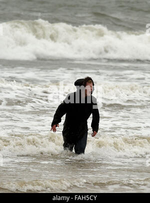 Boy in the sea fully clothed during stormy weather Stock Photo