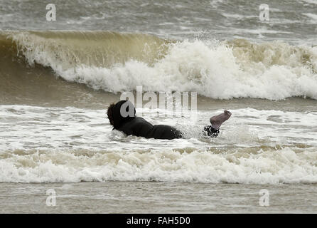 Boy in the sea fully clothed during stormy weather Stock Photo