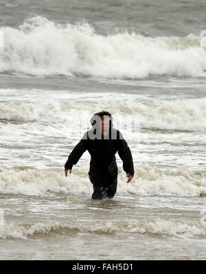 Boy in the sea fully clothed during stormy weather Stock Photo