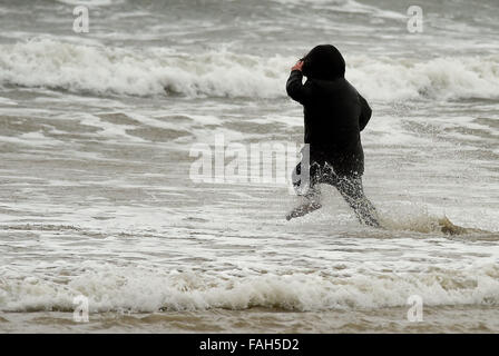 Boy in the sea fully clothed during stormy weather Stock Photo