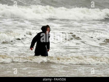 Boy in the sea fully clothed during stormy weather Stock Photo