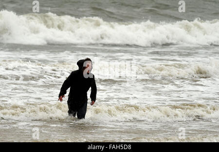 Boy in the sea fully clothed during stormy weather Stock Photo