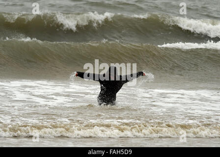 Boy in the sea fully clothed during stormy weather Stock Photo