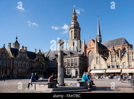 Tourist sitting by fountain in market square with Old Courthouse (Landhuis) and belfry. Grote Markt Veurne West Flanders Belgium Stock Photo