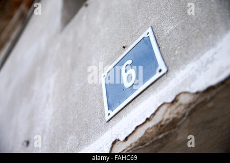 Metallic number six of house on wall Stock Photo