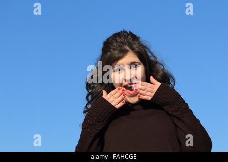 Girl with her hands over her mouth and eyes wide from shock. Stock Photo