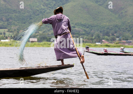 A fisherman from the Intha people rowing his boat on Inle Lake in Myanmar (Burma). The man is one of the leg rowers, who can row Stock Photo