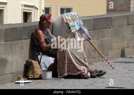 Czech naive street artist Antonin 'Tonda' Votava, also known as the Devil from the Charles Bridge, draws and sells self portraits on the Charles Bridge in Prague, Czech Republic, on June 8, 2003. Antonin Votava (1943 - 2009) worked as a street artist on the same place on the Charles Bridge for almost 40 years from 1969 until his death on October 22, 2009. His trademark red horns and tongue made him the living symbol of the Charles Bridge. Stock Photo