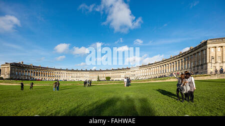 Groups of mainly Asian people pose for selfies and photographs on the lawns in front of the Royal Crescent in Bath UK Stock Photo