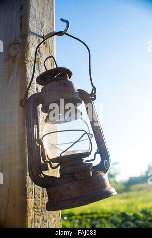 Old rustic kerosene lamp hanging from a post outdoors Stock Photo