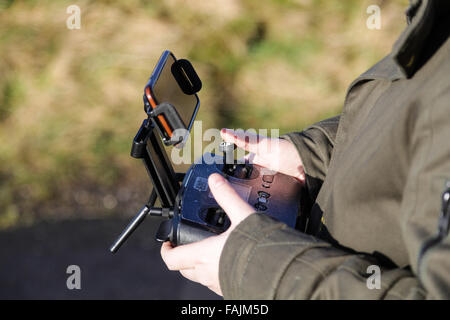Man outside controlling drone from mobile phone or tablet screen with thumbs on remote control sticks. Stock Photo