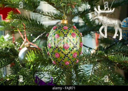 Christmas decorations on a Spruce Christmas Tree. Green with pink roses egg with other baubles and reindeer. Stock Photo