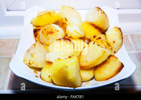 Roast potatoes roasted cooked cooking spuds on plate crispy edges ready to eat serve Stock Photo
