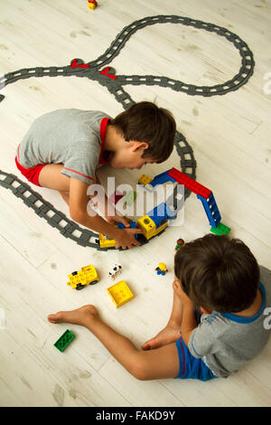 Toddler boys playing with toy train set. Stock Photo