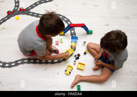 Toddler boys playing with toy train set. Stock Photo