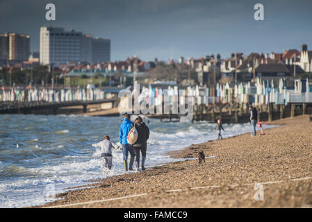 A family walk along the shoreline of Thorpe Bay beach in Southend on Sea, Essex, UK.