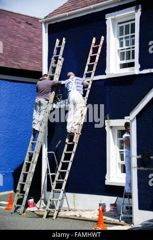 Two men painting a brightly colored house in a small seaside town, Stock Photo