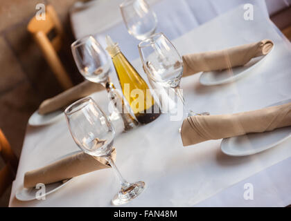 Simple Table setting in a restaurant with white tablecloth napkins and wine glasses. Stock Photo