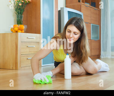 young housewife polishing parquet floor with furniture polish Stock Photo