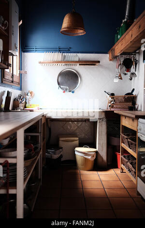 Simple, traditional, small kitchen with marble sink, tile floor and open cupboards Stock Photo