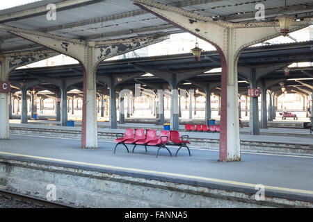 Red chairs in a romanian train station with symmetric pillars Stock Photo
