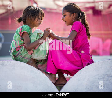 Two poor girls sitting on a wall, portrait, Pushkar, Rajasthan, India Stock Photo