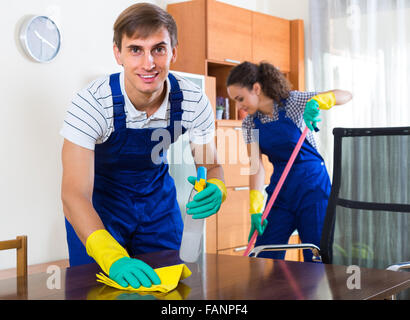 Team of positive professional cleaners dusting in ordinary office Stock Photo