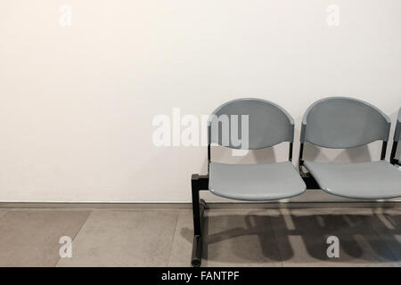 Two empty chairs by concrete wall with copyspace