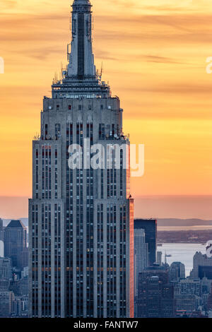Aerial view of the top of the Empire State Building skyscraper at sunset with a fiery sky. Midtown, Manhattan, New York City