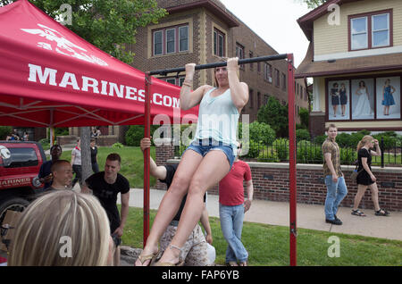 Young woman doing pull-ups exercise at the Marine Corps recruitment booth. Grand Old Day Street Fair. St Paul Minnesota MN USA Stock Photo