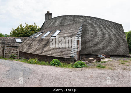 Herefordshire, UK. A self built house, timber clad, with a curved roof covered with wooden cedar shingles Stock Photo