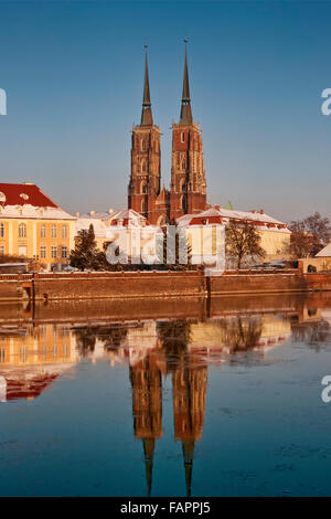Saint John the Baptist Cathedral mirrored in freezing water of Odra River at winter sunset at Ostrów Tumski in Wroclaw, Poland Stock Photo