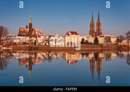 Holy Cross Church and Cathedral mirrored in freezing water of Odra River at winter sunset at Ostrów Tumski in Wroclaw, Poland Stock Photo
