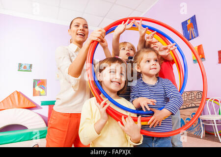 Portrait of kids with teacher looking though hoops Stock Photo