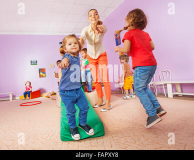 Teacher points running and jumping kids to viewer Stock Photo