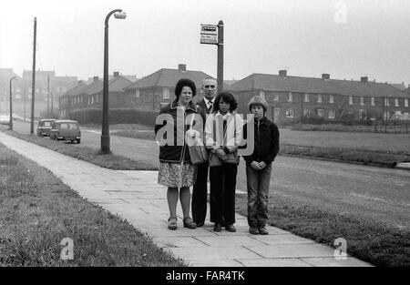Buttershaw Estate, Bradford, West Yorkshire, UK. A sprawling local authority 1950's council housing scheme. Black and white images from 1982 portray the gritty surroundings of a typical northern England working class sink estate. Family waiting at bus stop with two mini vans in background. Stock Photo