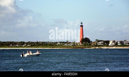 A fishing boat crosses in front of the Ponce de Leon inlet lighthouse. Stock Photo