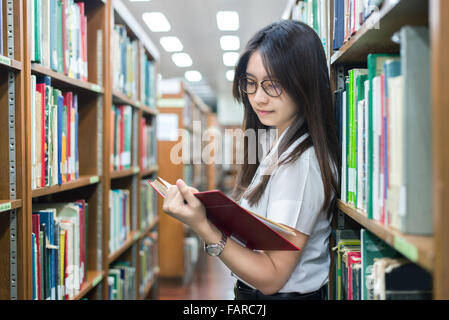 Asian student in uniform reading in the library at university Stock Photo