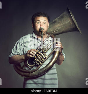 Portrait of an old man close up playing the trumpet. Studio photo Stock Photo