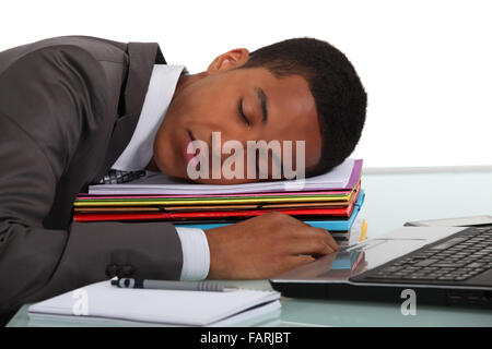 Worker sleeping on a stack of folders Stock Photo