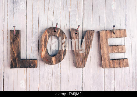 The word 'love' in wooden letters nailed on a rustic wooden background. Stock Photo