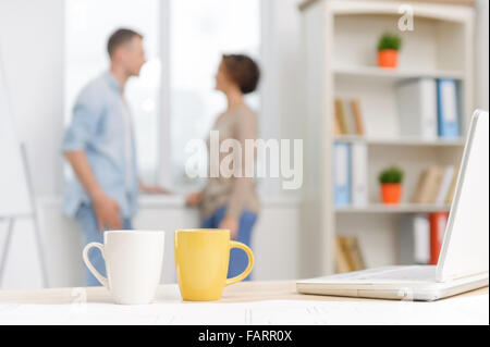 Two cups and a laptop on the desk. Stock Photo