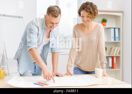 Two positive partners are collaborating over a drafting. Stock Photo